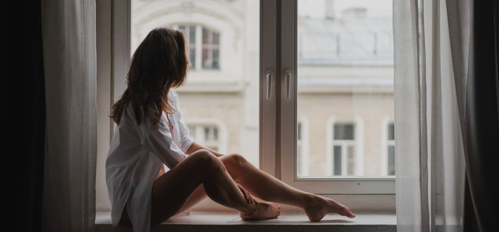 Sexy young woman looks through window.